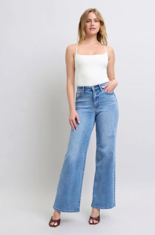 Woman wearing a white top and blue jeans on a plain background